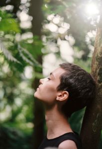 boy leaning back on tree